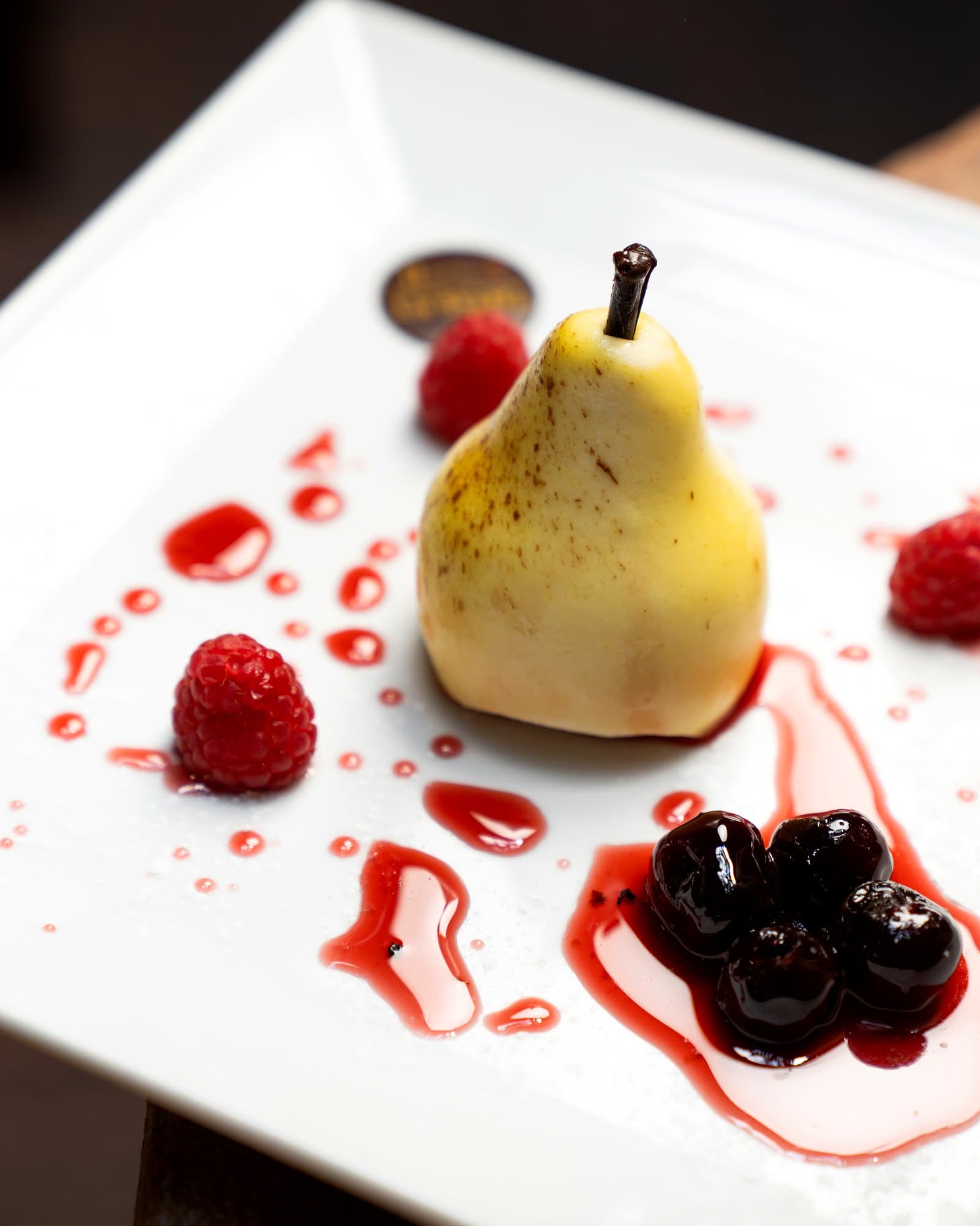Pera cotta al vino rosso con frutti di bosco e cioccolato