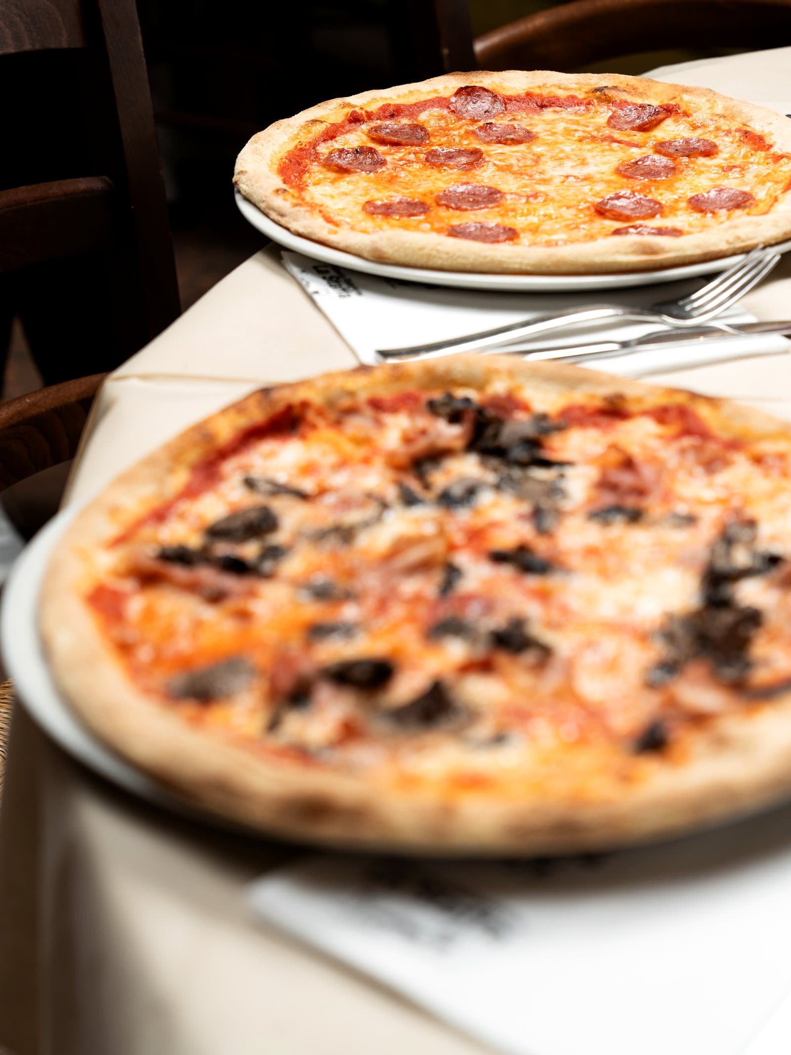 Due pizze al forno a legna appena servite sul tavolo apparecchiato de La Staffa